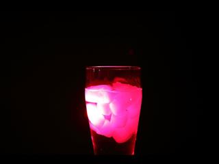 Beer glass with ice cubes illuminated with red laser light